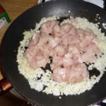 na patelni smaży się kurczak pokrojony w niedużą kostkę oraz cebula