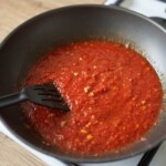 w woku gotuje się sos pomidorowy do penne arrabiata