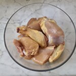 kawałki kurczaka z kością przyprawione solą i pieprzem znajdują się w szklanej misce