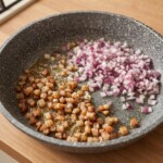 na dużej patelni smaży się drobno siekana czerwona cebula i tak samo krojona słonina wędzona