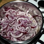 w garnku smaży się czerwona cebula pokrojona w piórka