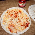 na tortille nałożony jest ostry sos oraz starty ser żółty