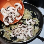 na dużej patelni smaży się drobno siekana cebula i krojone w plasterki pieczarki