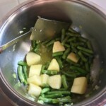 w garnku smażą się fasolka szparagowa i ziemniaki pokrojone w kostkę