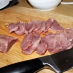 polędwiczka wieprzowa pokrojona w plastry leży na desce kuchennej
