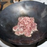 w woku smaży się wieprzowina pokrojona w małe kawałki