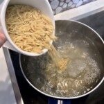 makaron orzo wrzucany jest do garnka z gotującą się wodą