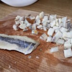 drobno pokrojony filet śledziowy leży na desce kuchennej