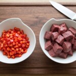 wołowina pokrojona w kostkę w misce oraz drobno siekana w kostkę czerwona papryka