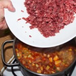 mięso mielone wołowe wrzucane jest do garnka z gotująca się zupą meksykańską