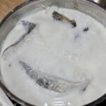 w garnku gotują się kawałki dorsza ze skórą