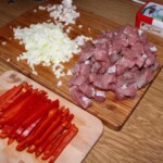wieprzowina pokrojona jest w nieduża kostkę, a papryka czerwona w paski
