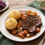 pieczeń na kwaśno sauerbraten podana z warzywami korzeniowymi i knedlami