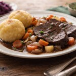 pieczeń na kwaśno sauerbraten podana z warzywami korzeniowymi i knedlami