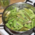 w garnku gotują się kawałki końcówek zielonych szparagów