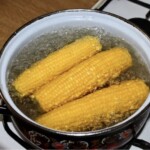 w garnku gotują się dwa kolby kukurydzy