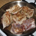 na dużej patelni smażą się kawałki żeberek wieprzowych