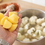 w garnku gotują się różyczki kalafiora i krojone w kostkę obrane ziemniaki