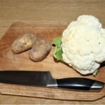 kalafior i dwa ziemniaki na drewnianej desce