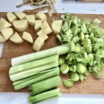 na desce kuchennej leżą pokroje w plastry pory oraz kawałki ziemniaków