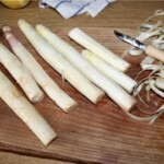 obrane białe szparagi leżą na desce kuchennej