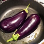 bakłażany przekrojone wzdłużna połowę smażą się na patelni wnętrzami do spodu
