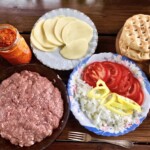 pljeskavica z serem oraz dodatki w postaci pomidorów, papryki oraz chlebków pita