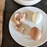 dwa jajka ugotowane na twardo są obierane