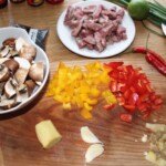 kolorowe papryki pokrojone są w drobną kostkę, grzyby w kawałki, a mięso w paski