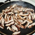 na patelni smaży się mięso kurczaka pokrojone w paski