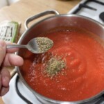 w garnku gotuje się miąższ z pomidorów z suszonym oregano
