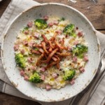 Risotto przygotowane z ryżu duszonego na białym winie i szalotce podane z gotowanym brokułem i smażoną wędzonką.