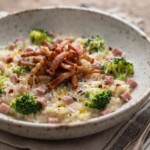 Risotto przygotowane z ryżu duszonego na białym winie i szalotce podane z gotowanym brokułem i smażoną wędzonką.