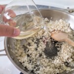 dolewanie wina do smażącego się na patelni ryżu na risotto z cukinią