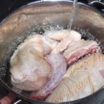 w garnku znajdują się kawałki kurczaka, które zalewane są zimną wodą