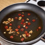 na dużej patelni smaży się siekany czosnek oraz czerwone peperoncino