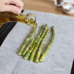 zielone szparagi na blasze do pieczenia polewane oliwą