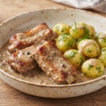 żeberka wieprzowe duszone z czosnkiem i chilli podane na talerzu z gotowanymi ziemniakami