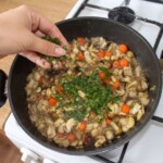 na dużej patelni smaży się drobno siekana cebula warzywa korzeniowe oraz grzyby gąski