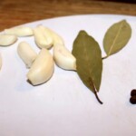 obrane ząbki czosnku oraz liści laurowe na blacie kuchennym