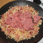 na patelni smaży się drobno pokrojony boczek wędzony, cebula oraz mielone mięso