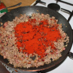 na patelni smaży się drobno pokrojony boczek wędzony, cebula oraz mielone mięso