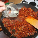 na patelni smaży się drobno pokrojony boczek wędzony, cebula oraz mielone mięso