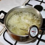 w dużym garnku smażą się kawałki dorsza w cieście z mąki żytniej