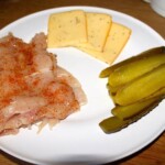 kotlety z piersi kurczaka, plastry ogórka kiszonego i plasterki sera na talerzu