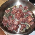 na patelni smaży się wieprzowina pokrojona w niedużą kostkę