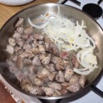 na dużej patelni smaży się pokrojona w nieduża kostkę wieprzowina na gulasz razem z krojoną w piórka cebulą
