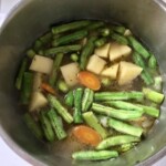 w garnku gotuje się zielona fasolka szparagowa i ziemniaki w kostkę pokrojone