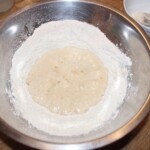 w dużej misce znajduje się mąka i zaczyn drożdżowy na pączki