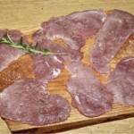 plastry polędwiczki wieprzowej leżą na desce kuchennej